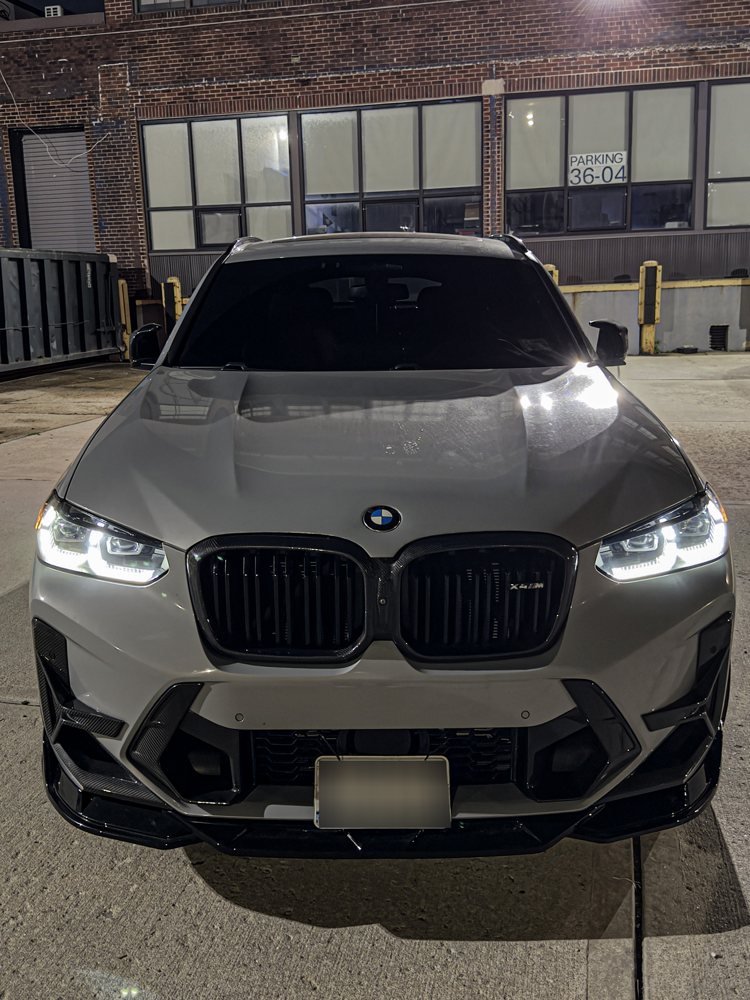 BMW X3 M with the HPRM front lip splitter, head-on at night